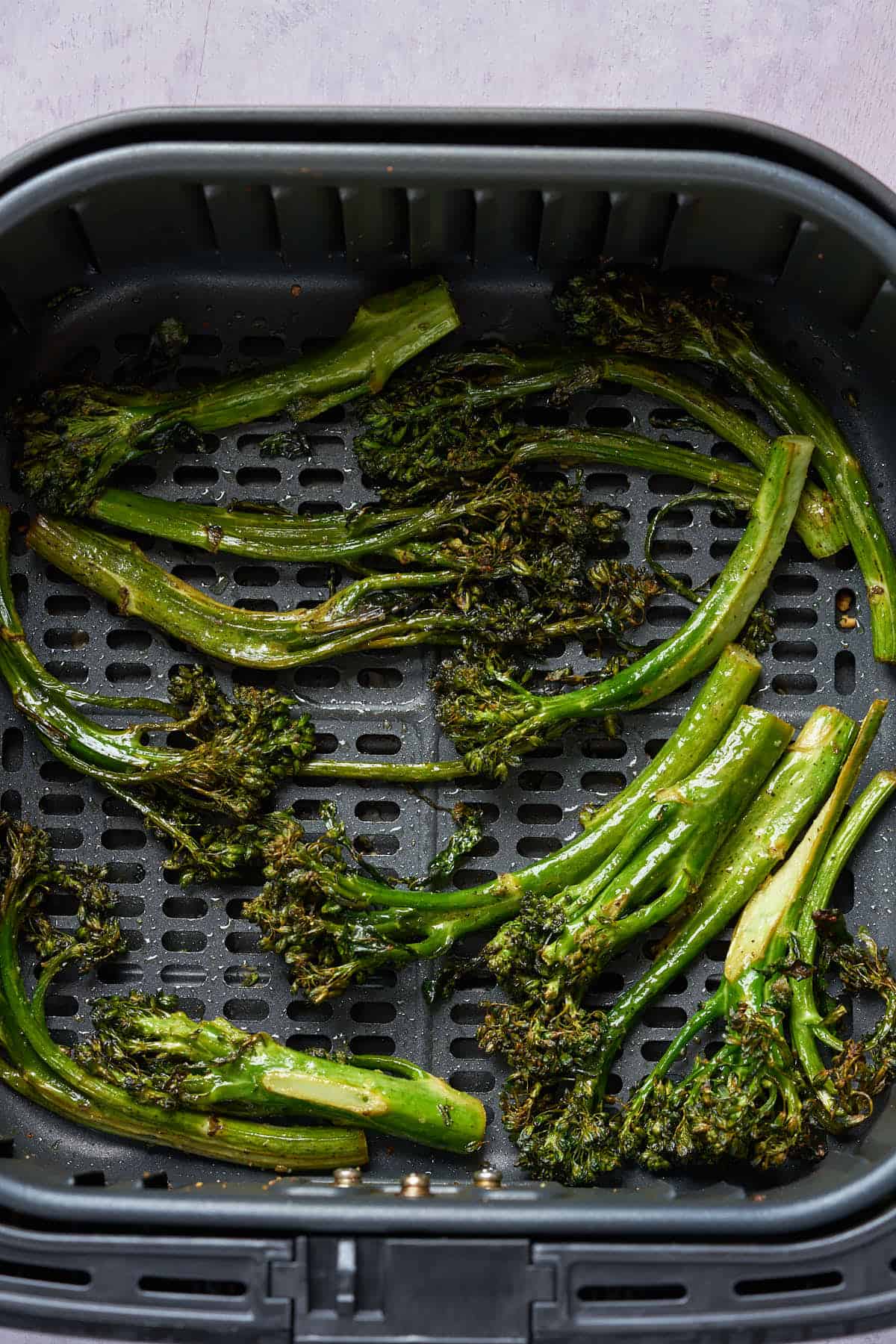 Air fryer broccolini in the air fryer basket.