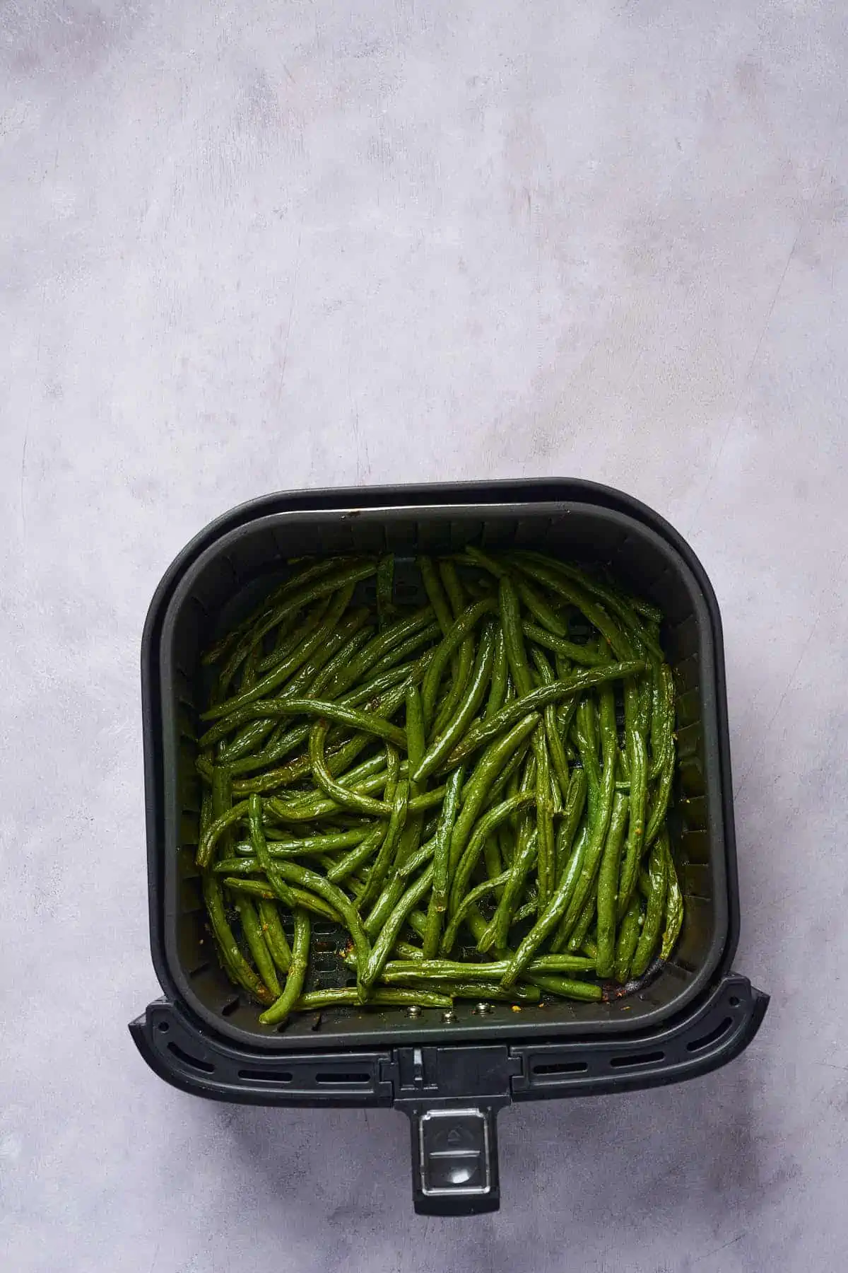 Cooked garlic green beans in the air fryer basket.