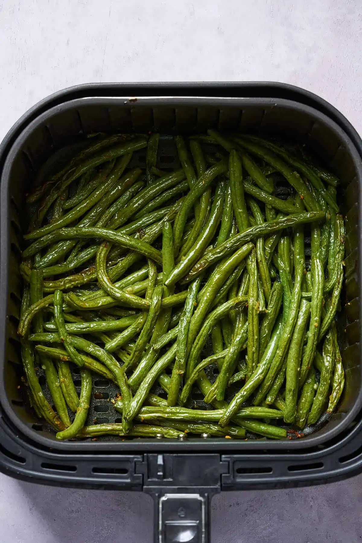 Air fried garlic green beans in the air fryer basket.