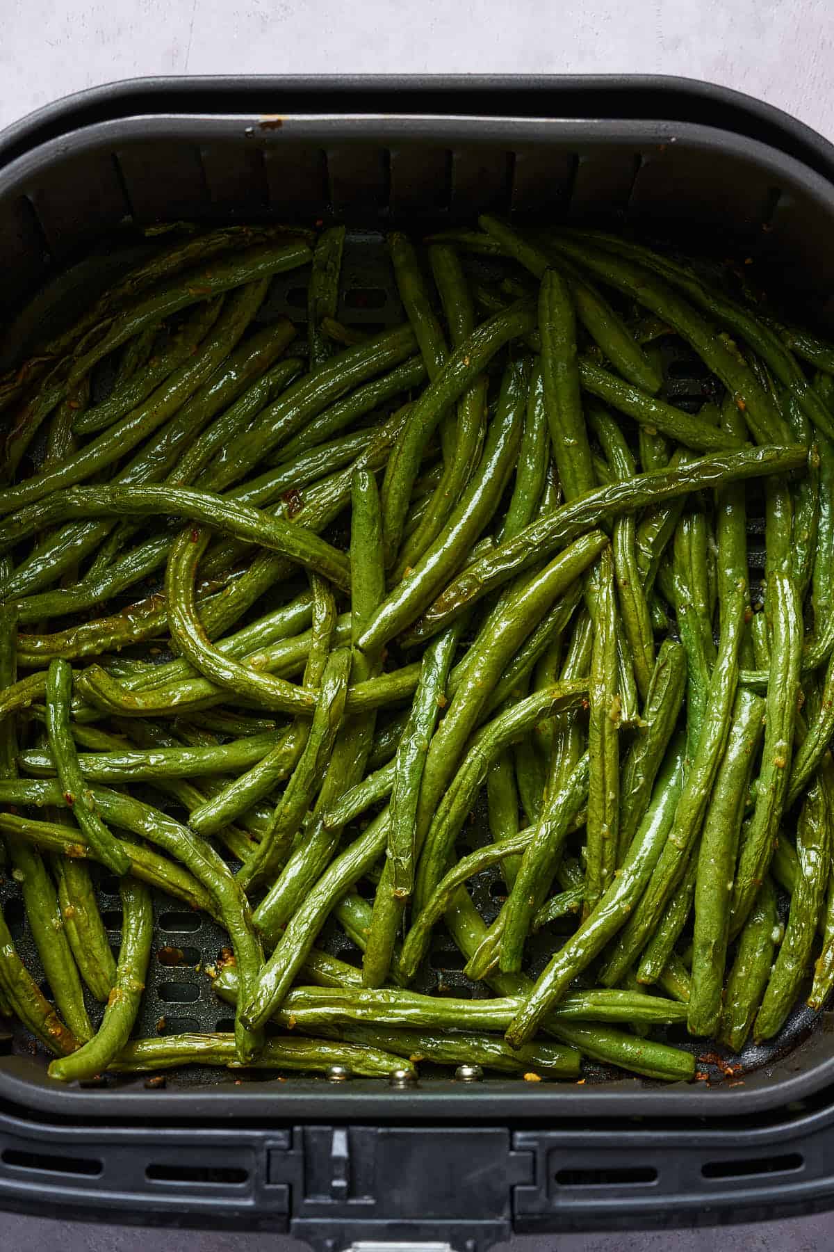 Air fryer garlic green beans in the air fryer basket.