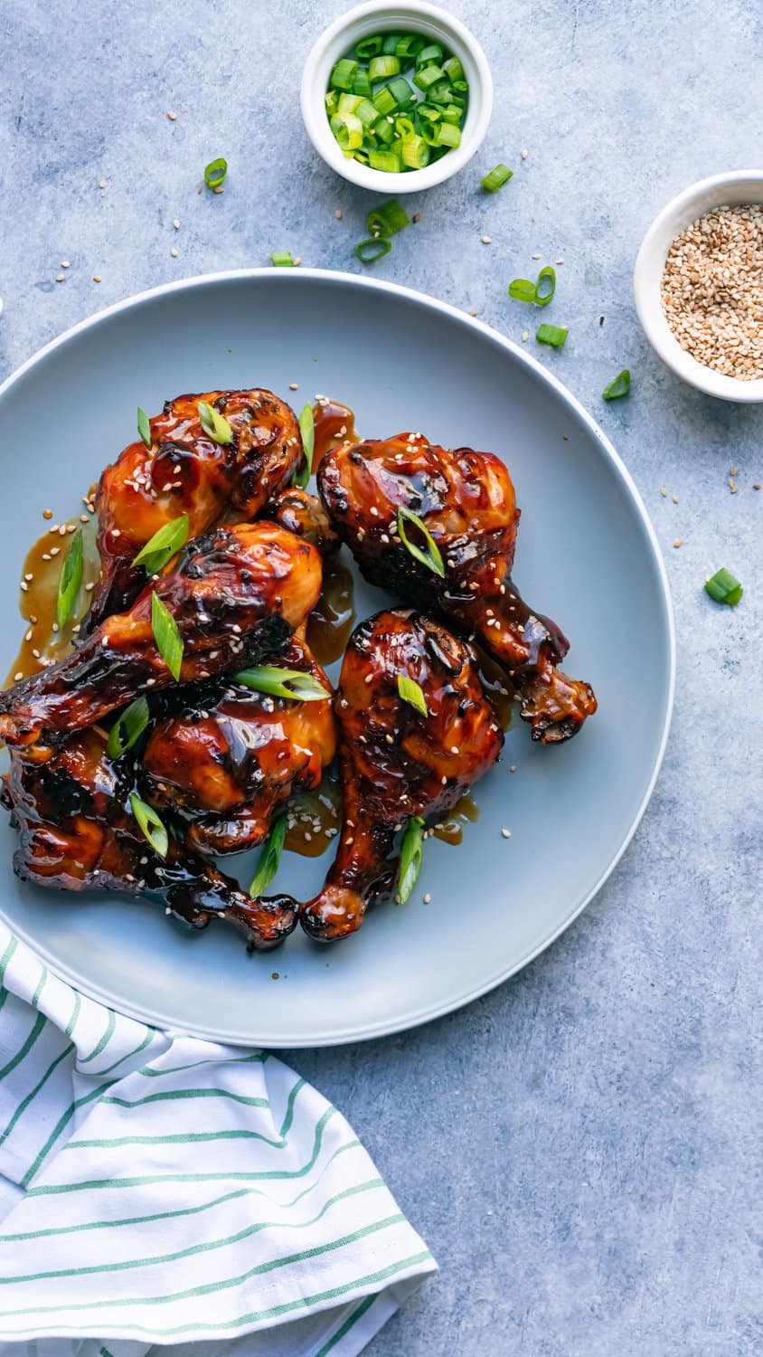 Air fryer teriyaki chicken legs served with green onion and sesame seeds.