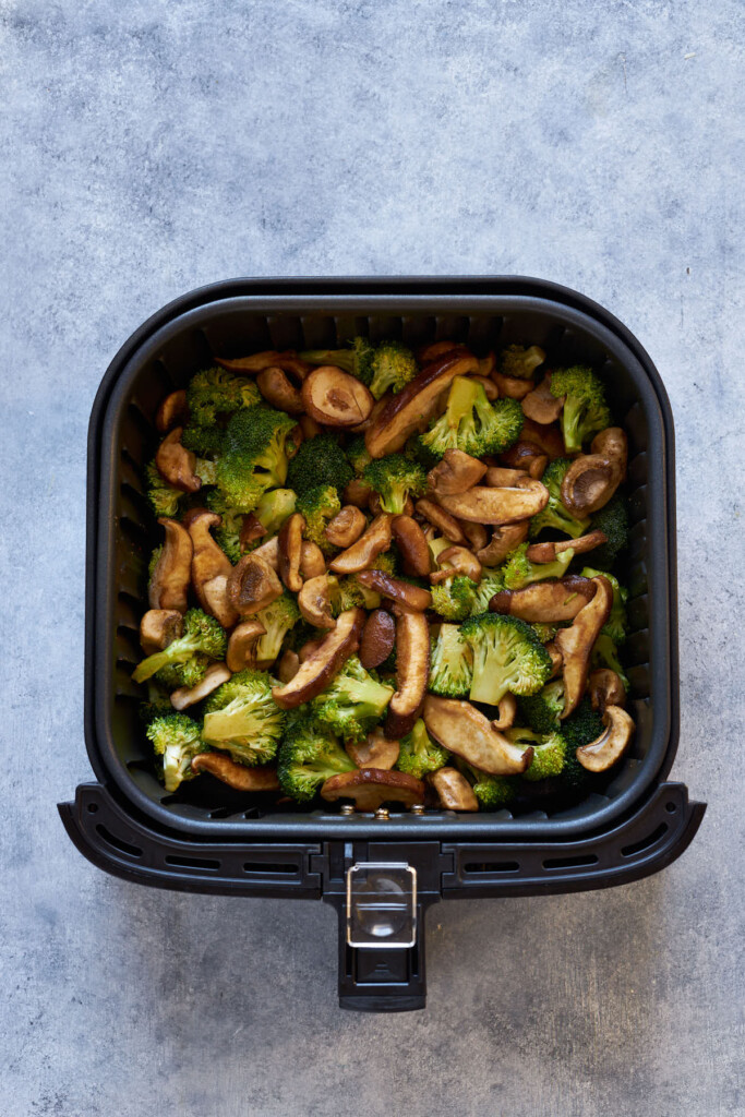 Mushrooms and broccoli in the air fryer basket.