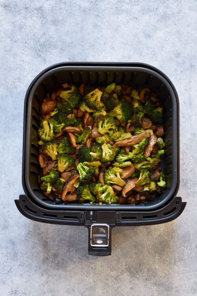 Air fried mushrooms and broccoli in the air fryer basket.