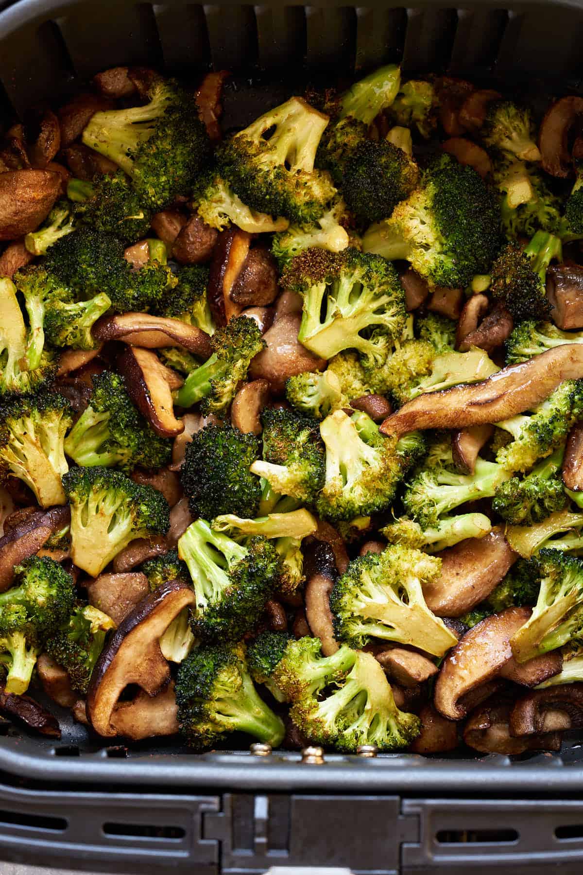 Air fryer broccoli and mushrooms in the air fryer basket.