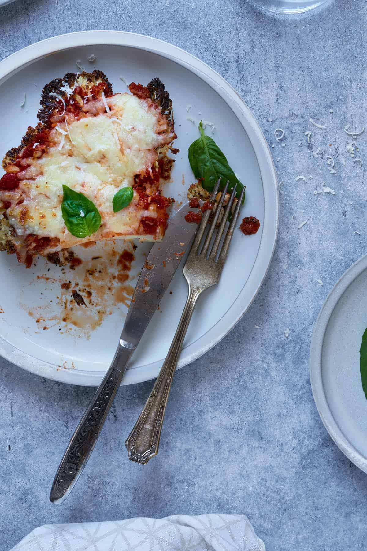 Vegetable parmesan garnished with fresh basil on a plate.