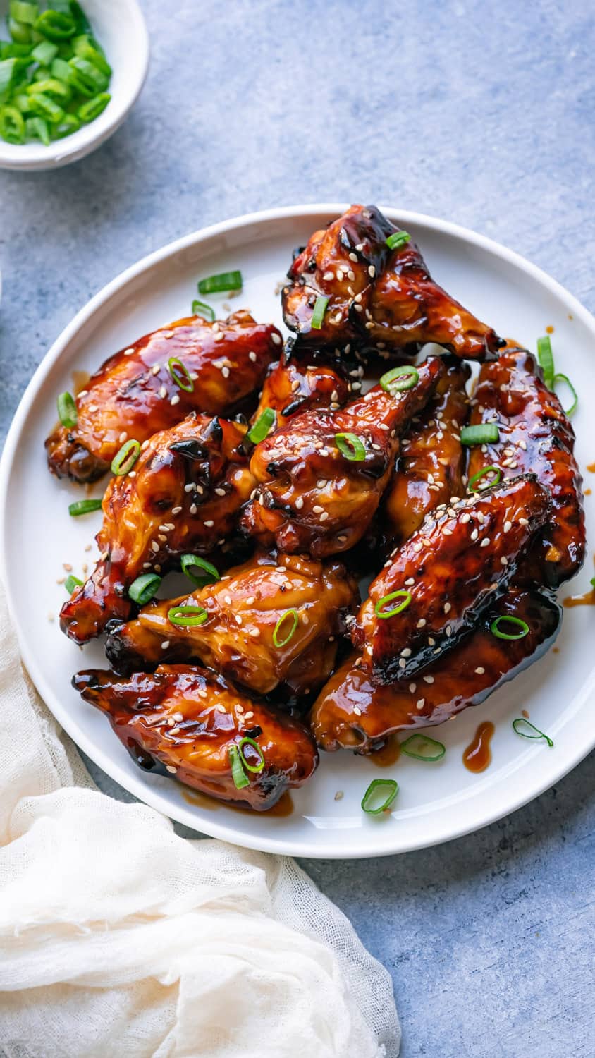 Air fryer teriyaki chicken wings served with green onion on a plate.