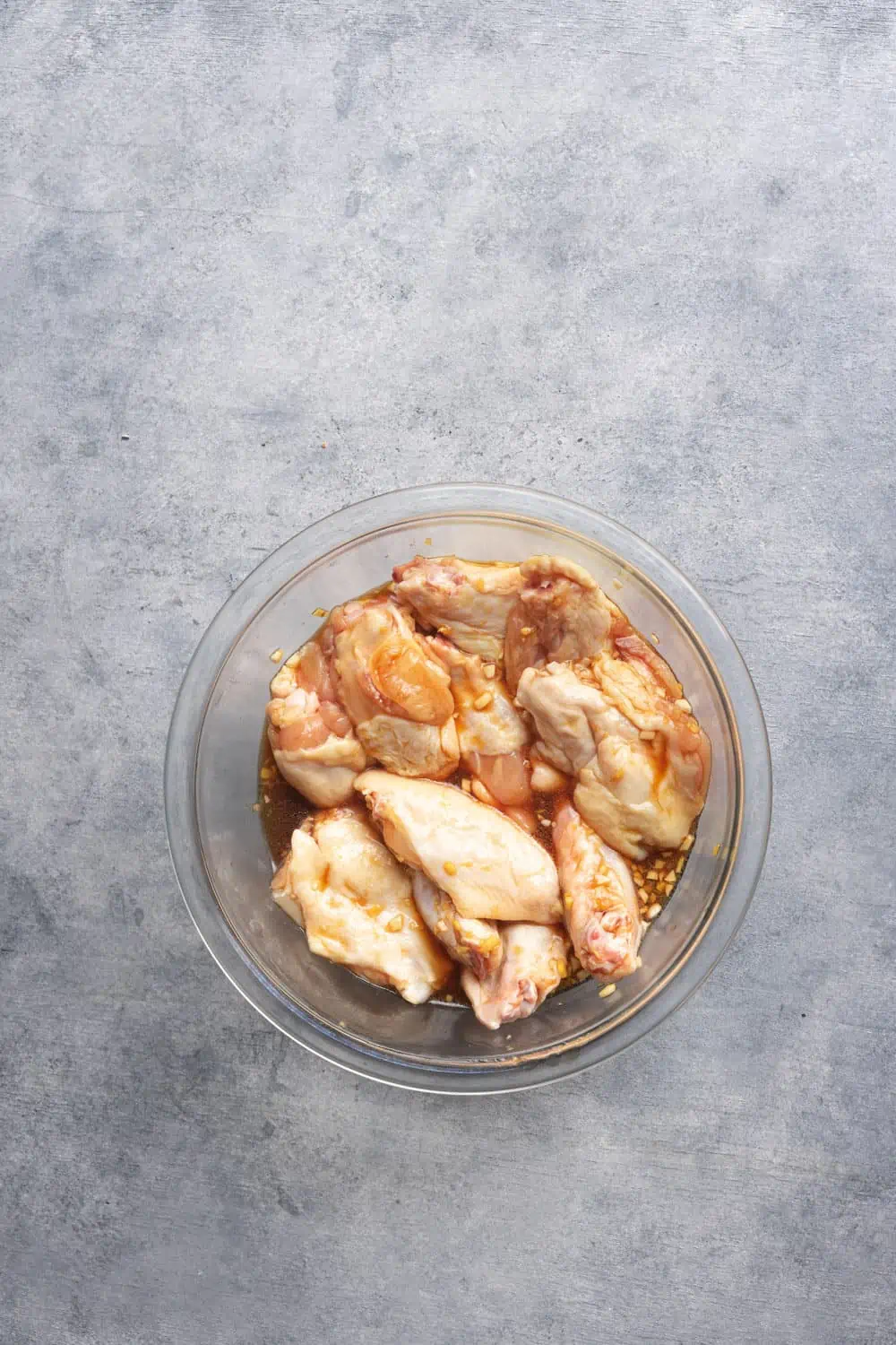 Chicken wings marinating in a bowl.