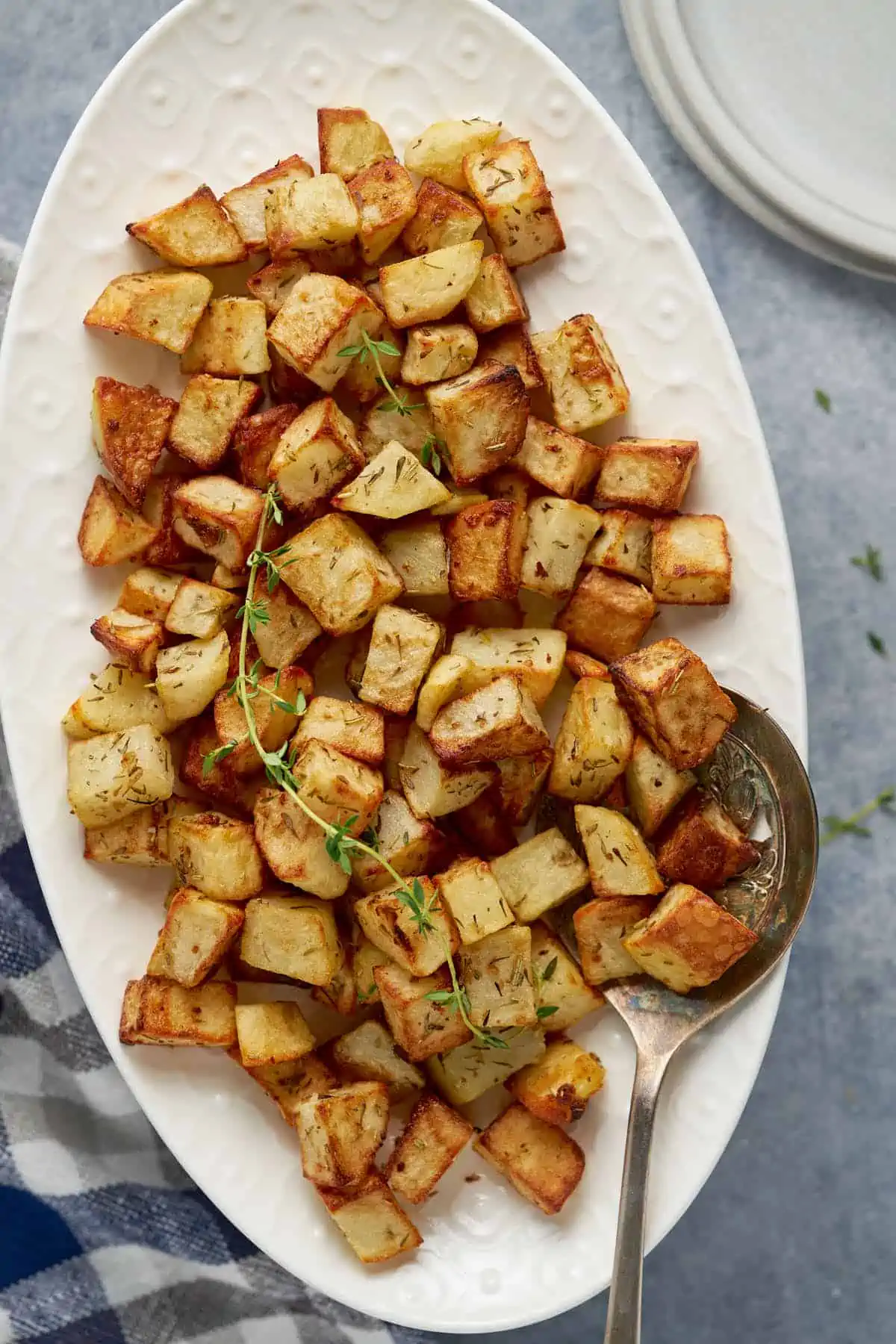 Air fryer potato cubes serve on a plater with fresh herbs.