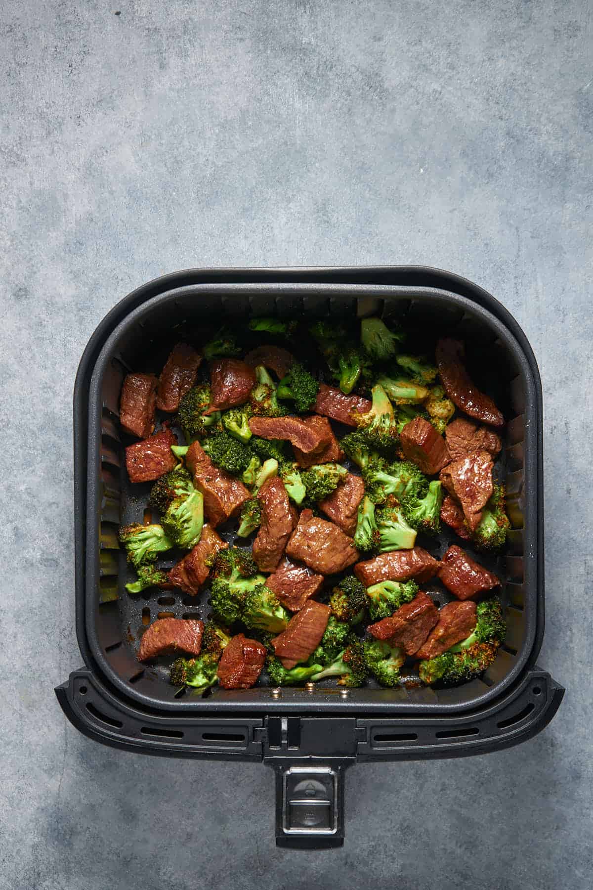 Beef and broccoli in the air fryer basket after cooking.