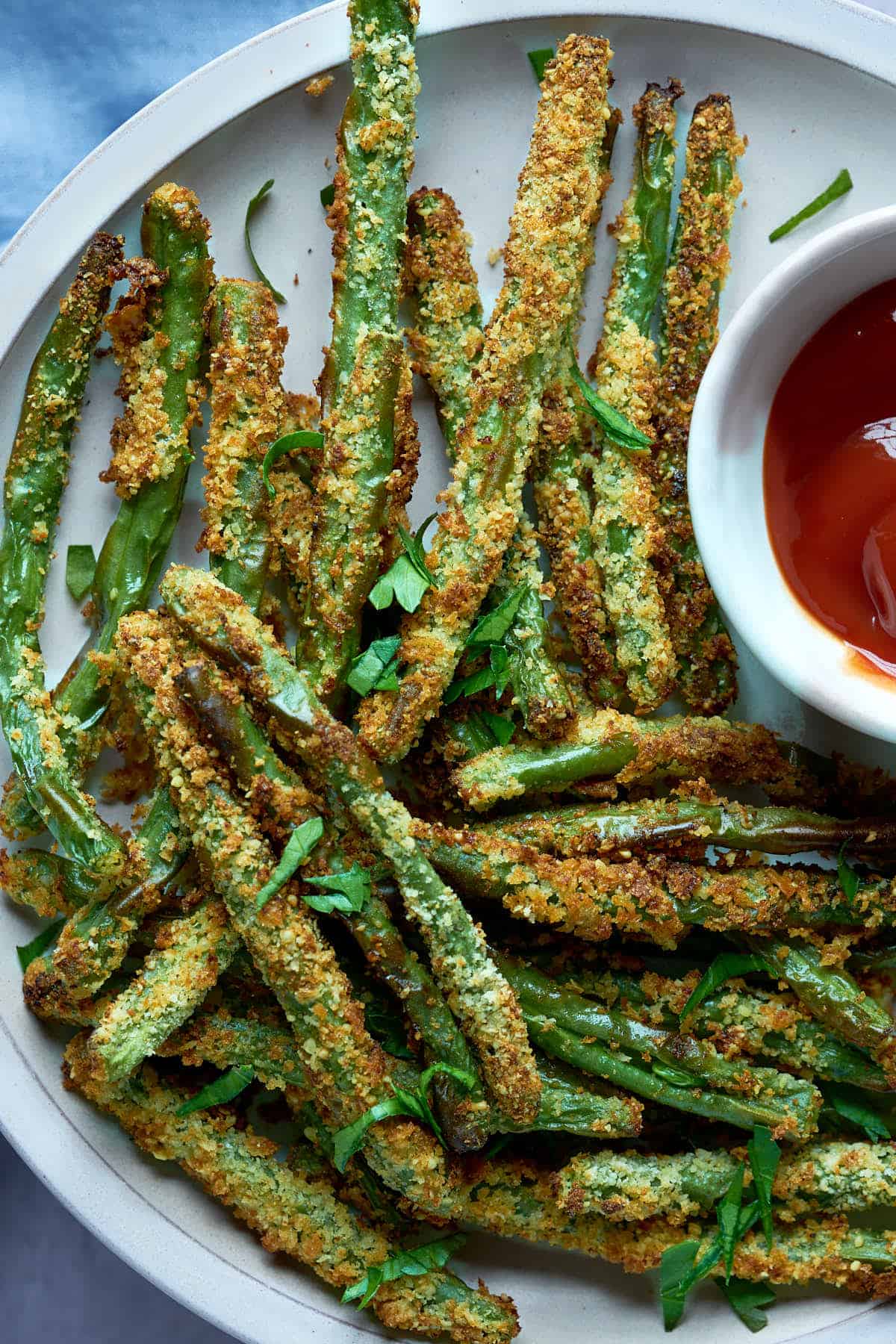 Crunchy green bean fries on a plate with dipping sauce.