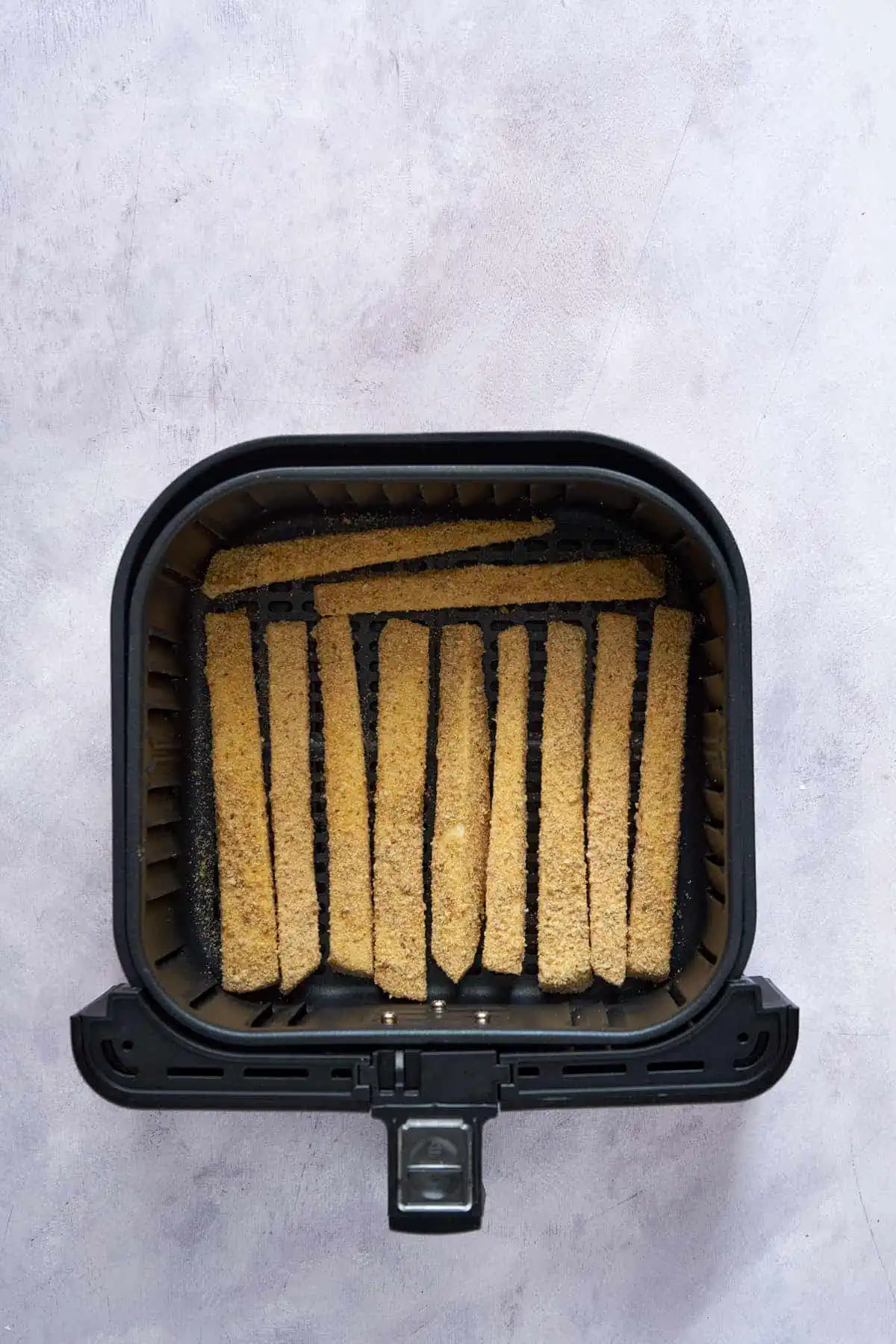 Coated eggplant sticks in the air fryer basket.