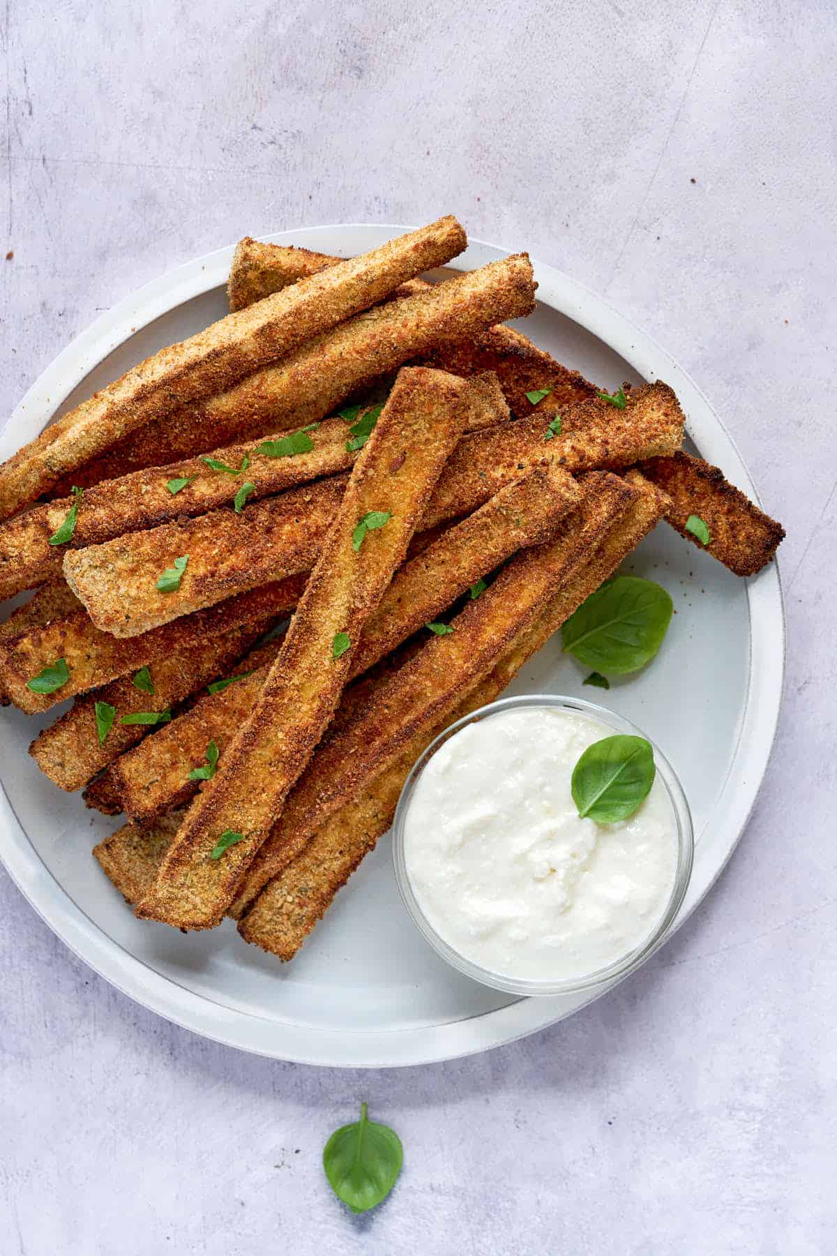 Eggplant fries served with dipping sauce and sprinkled with fresh herbs.