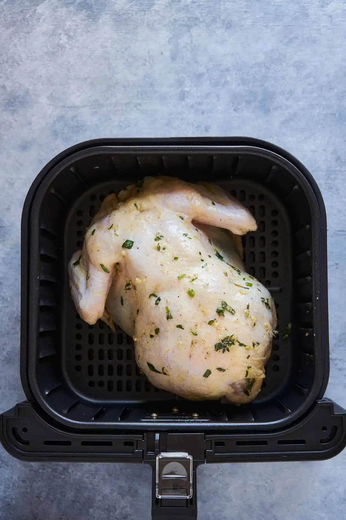 Breast side down, whole chicken in the air fryer basket.