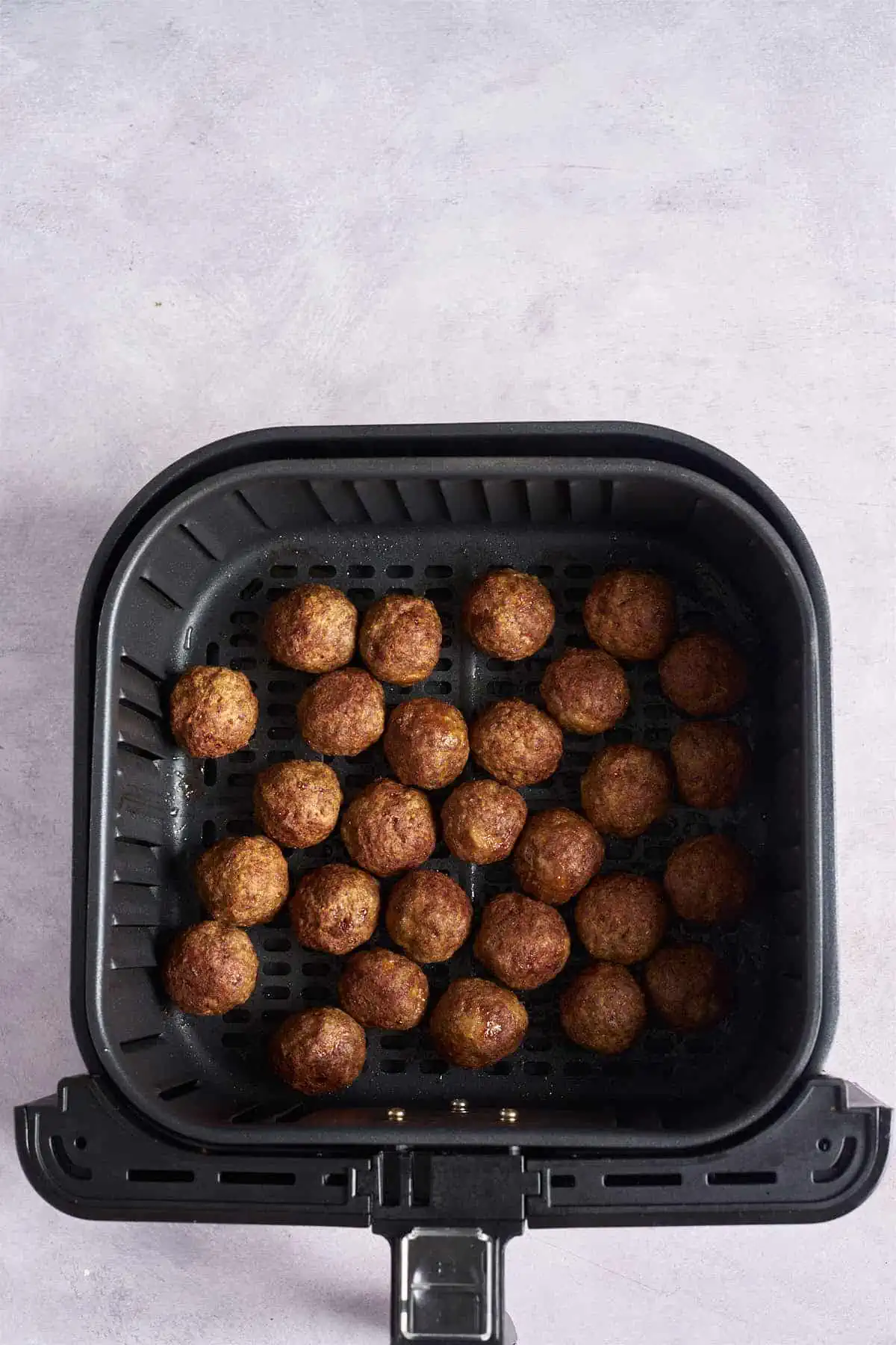 The meatballs in the air fryer basket after cooking.