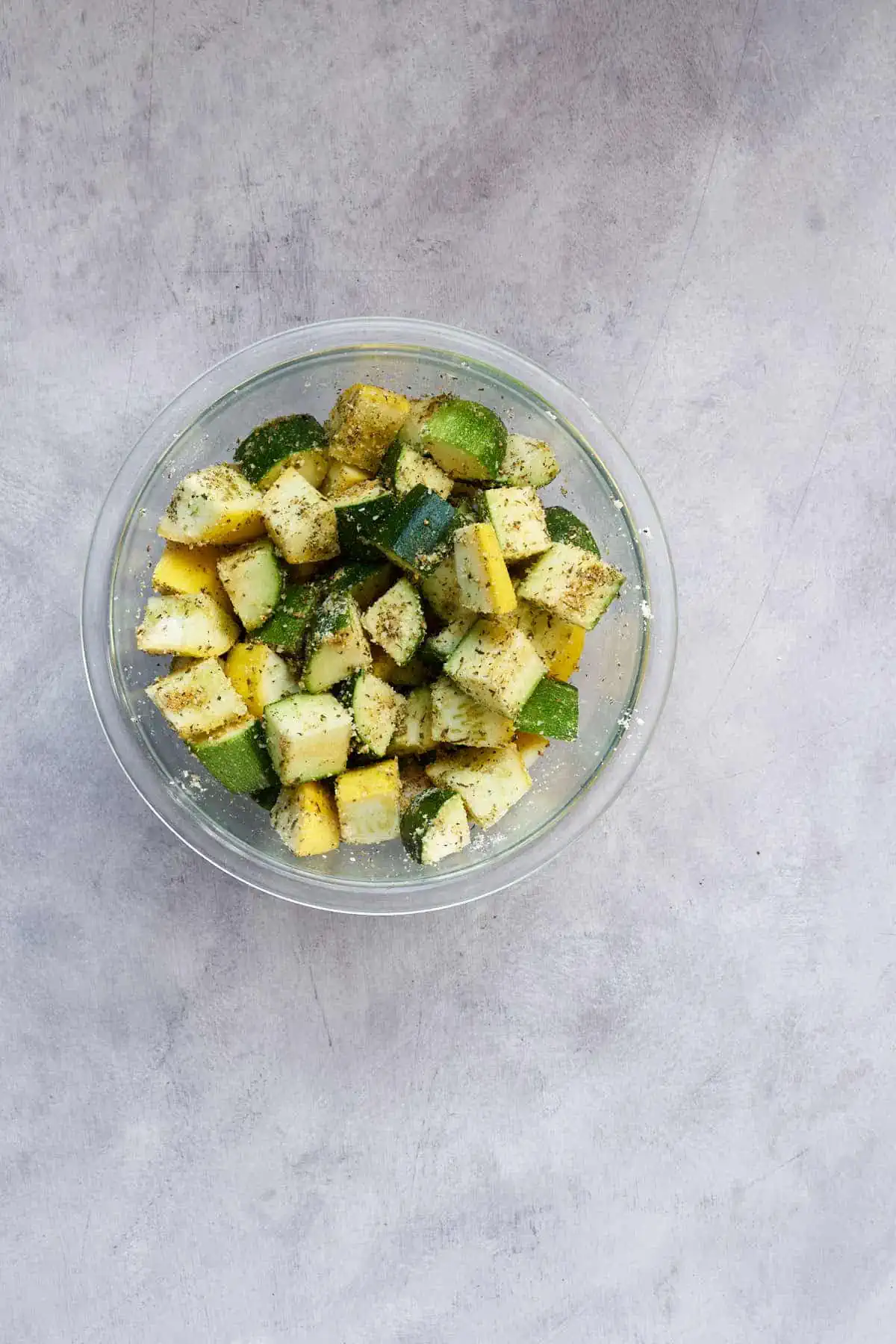 Zucchini and yellow squash in a bowl mixed with the seasoning.