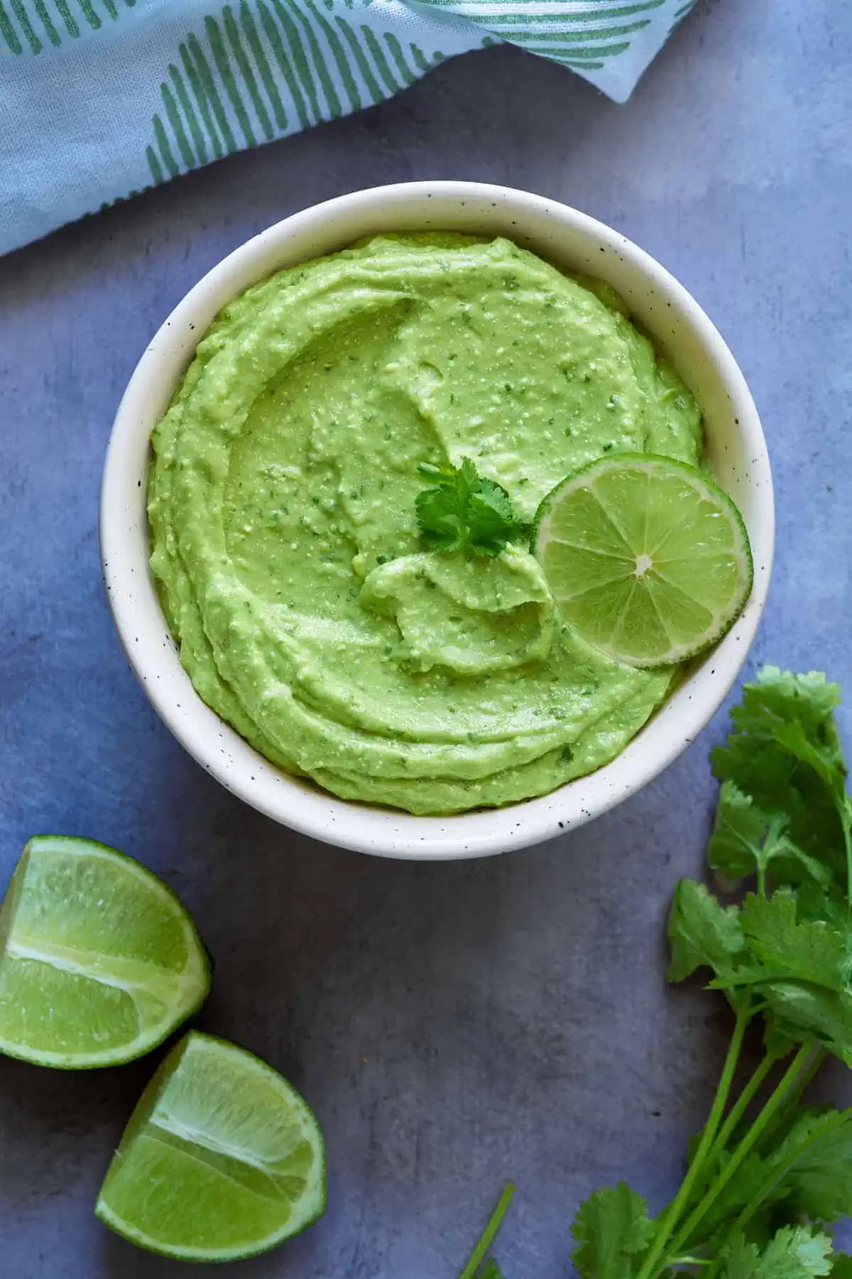 Avocado feta dip served in a small bowl and garnished with fresh cilantro and lime.