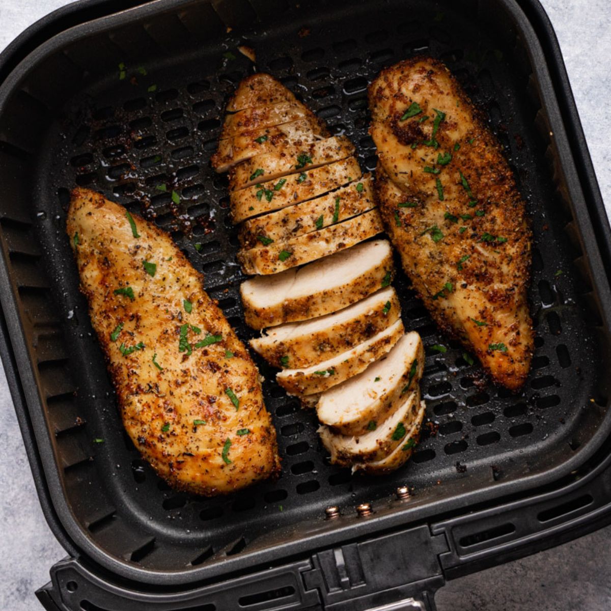 cooked chicken breast in the air fryer basket.