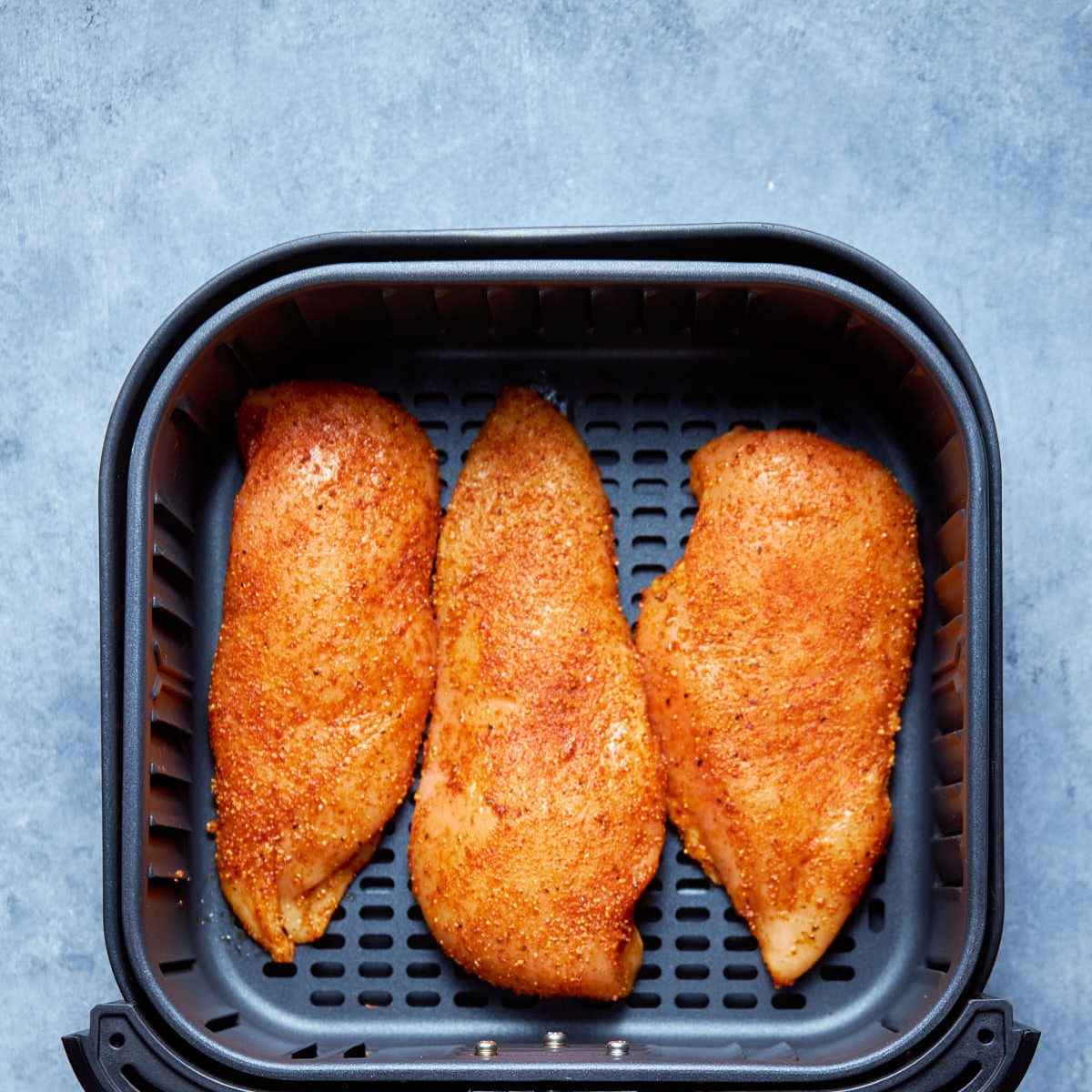 air fryer chicken breast with seasoning and oil before cooking in the basket.