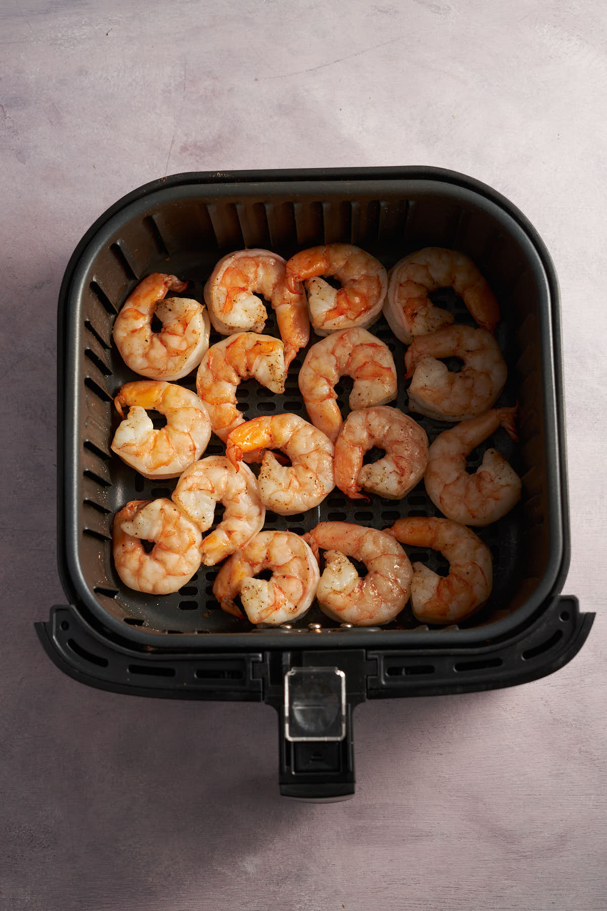 Cooked shrimp in an air fryer basket after air frying