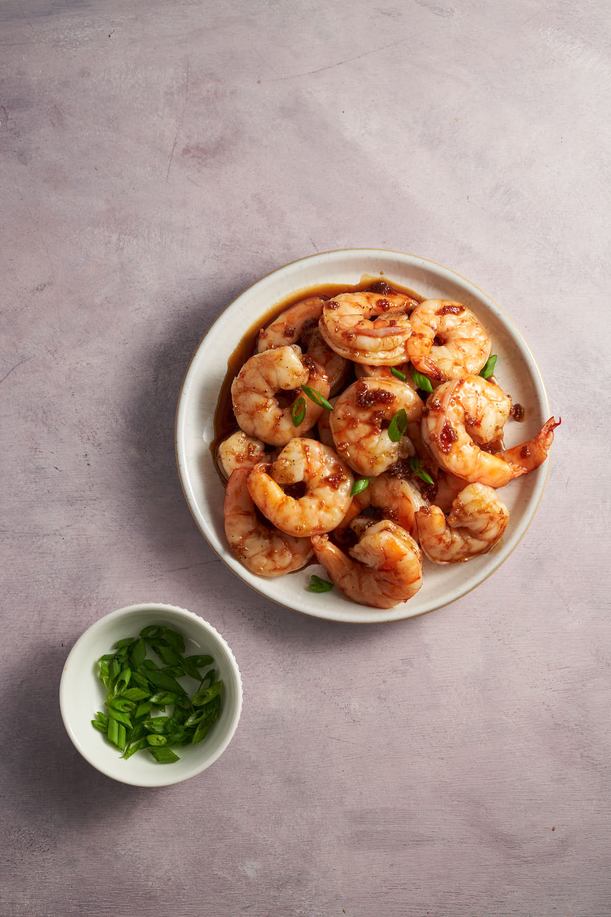 Bowl of air fryer honey garlic shrimp topped with sliced green onions