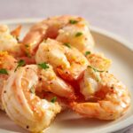 Air fryer lemon garlic shrimp served on a white plate with fresh lemon zest