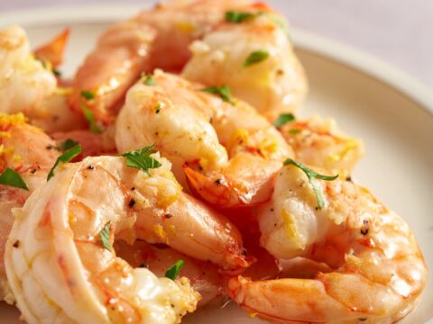 Air fryer lemon garlic shrimp served on a white plate with fresh lemon zest