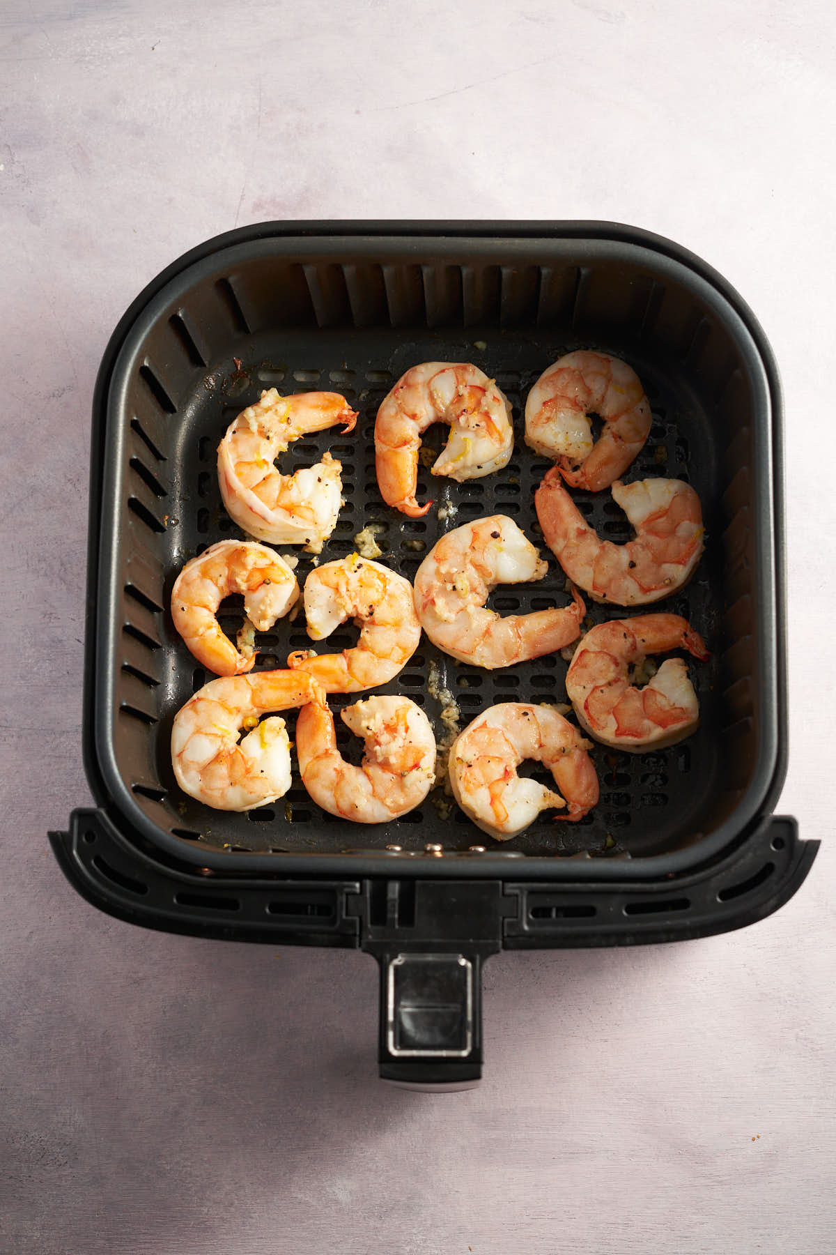 Lemon garlic shrimp cooking in an air fryer basket