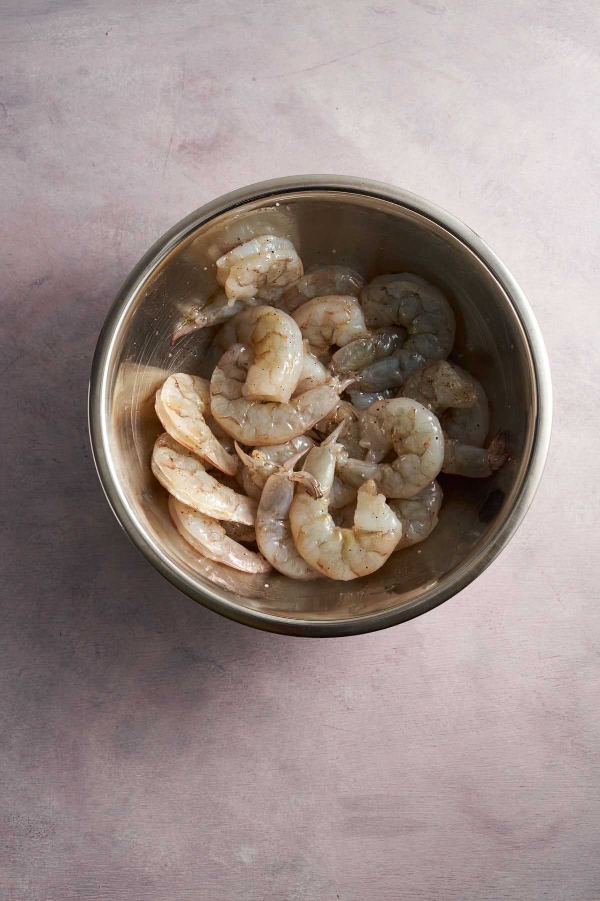 Seasoning the shrimp in a mixing bowl.