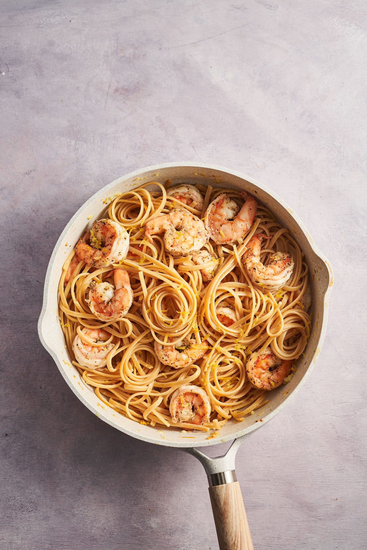 Shrimp and pasta cooking together in a skillet.