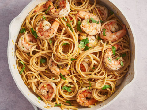 Overhead view of lemon garlic shrimp pasta in a skillet with parsley and lemon zest