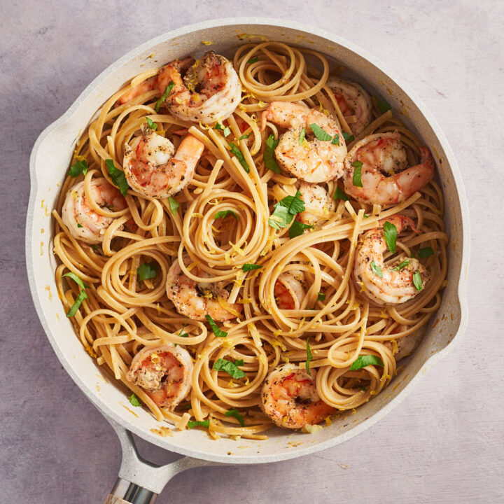 Overhead view of lemon garlic shrimp pasta in a skillet with parsley and lemon zest
