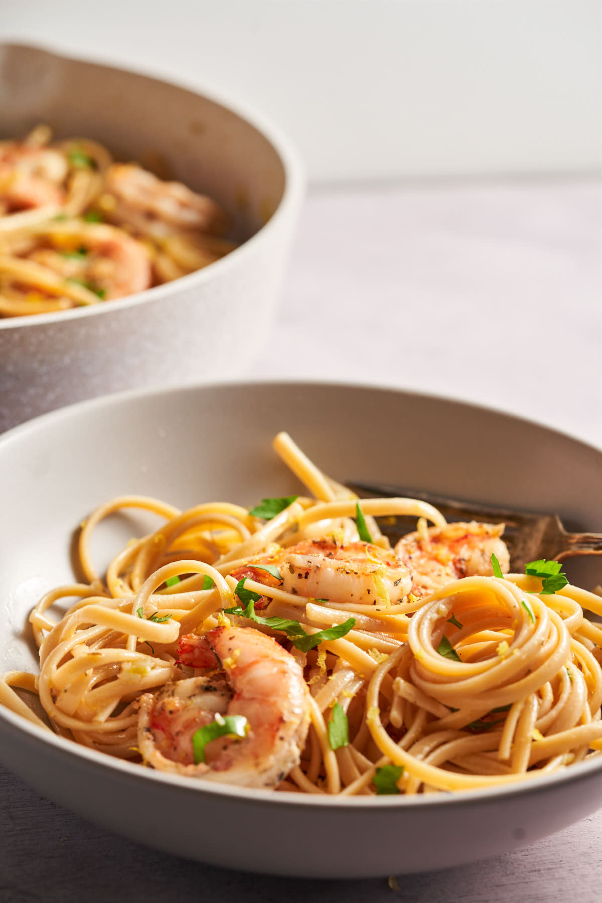 Bowl of shrimp pasta with a second serving in the background.