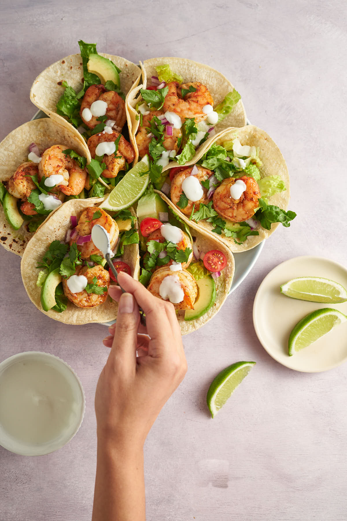 Hand spooning sauce over Old Bay shrimp tacos