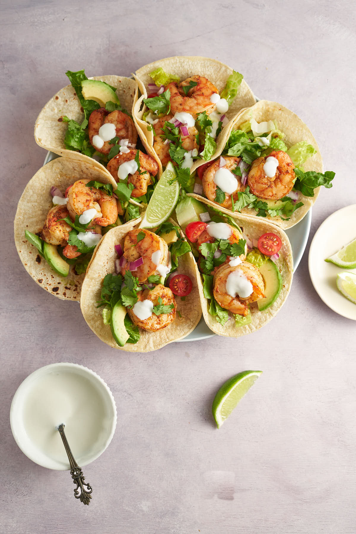 Plate of Old Bay shrimp tacos with lettuce, avocado, and lime.