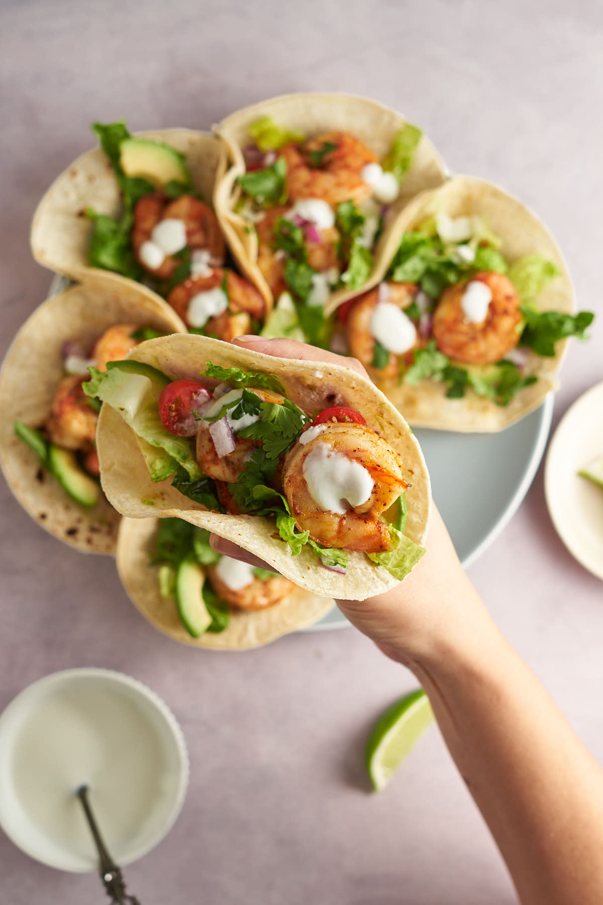 Hand holding an Old Bay shrimp taco filled with lettuce, avocado, and shrimp.