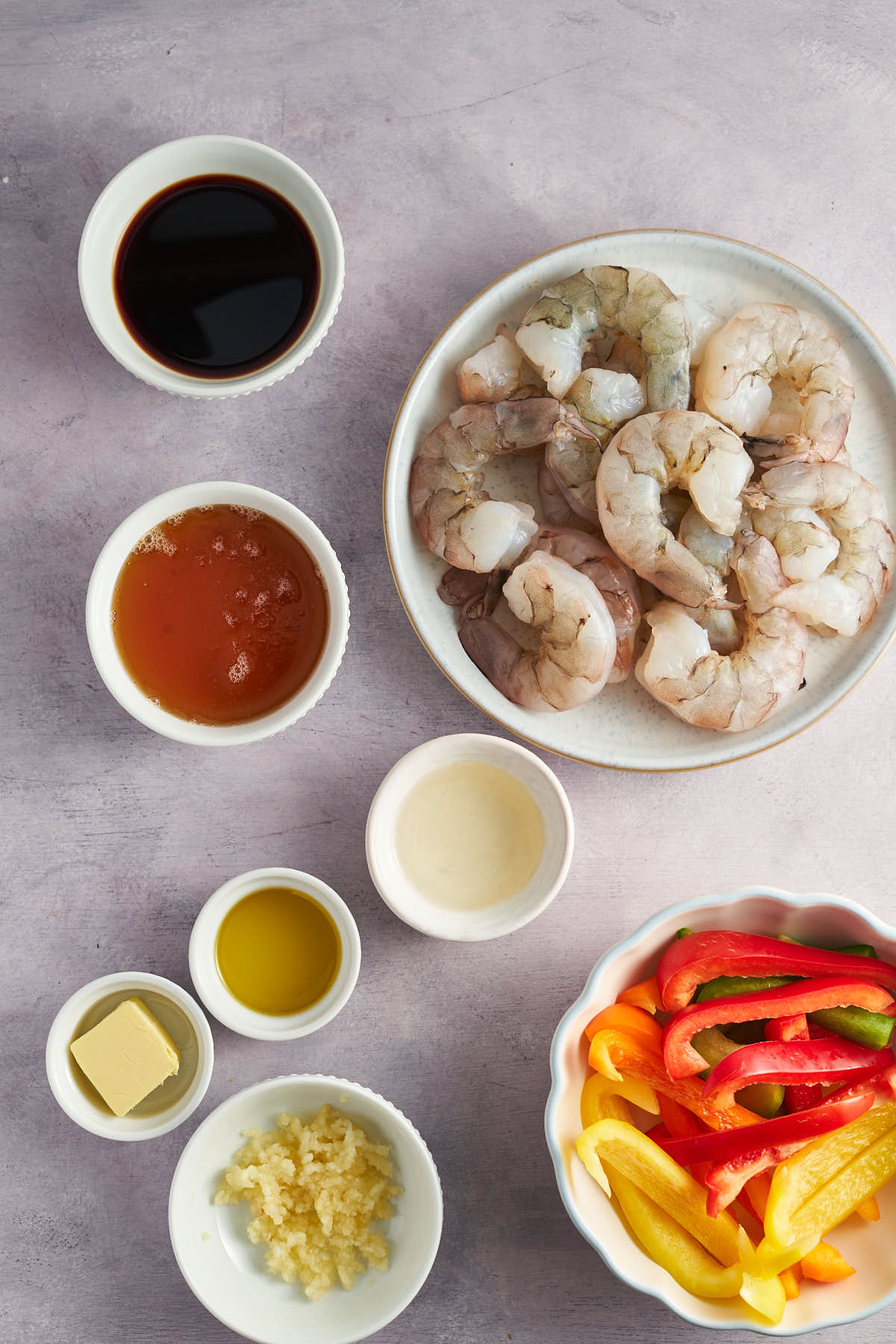 Shrimp, sliced bell peppers, and ingredients for honey garlic sauce arranged in bowls.