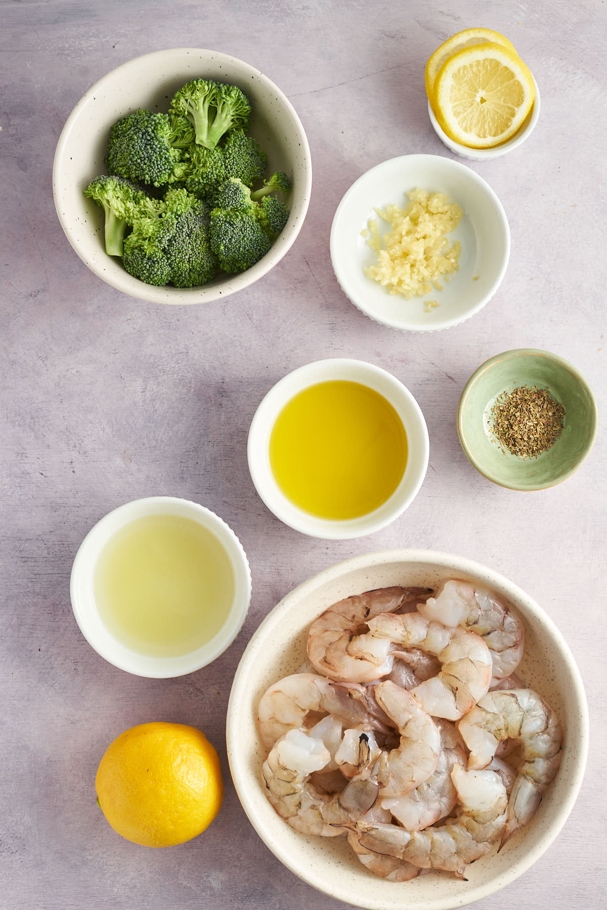 Shrimp, broccoli, lemon, minced garlic, oil, and seasonings for lemon garlic shrimp sheet pan dinner